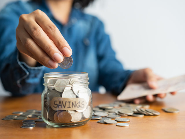 woman putting coin in savings jar