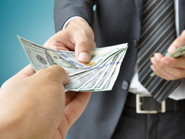businessman handing money to another hand